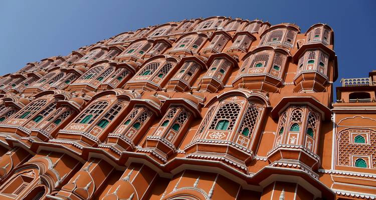 Aufwärtsgerichteter Winkel der kunstvoll verzierten rosa Sandsteinfassade des Hawa Mahal vor einem klaren Himmel