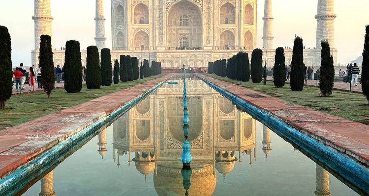 Reflejo perfecto del Taj Mahal en la larga piscina central enmarcada por cipreses al amanecer.