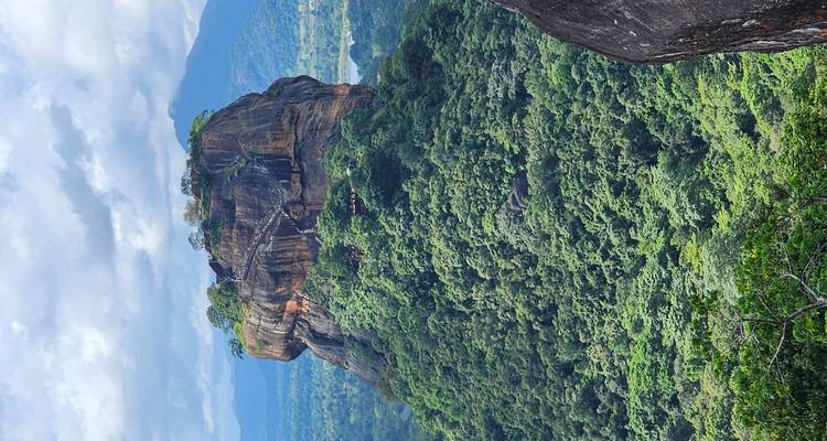 Der hoch aufragende, flachgipflige Sigiriya-Felsenfestung erhebt sich über dichten tropischen Wald und entfernte Berge.
