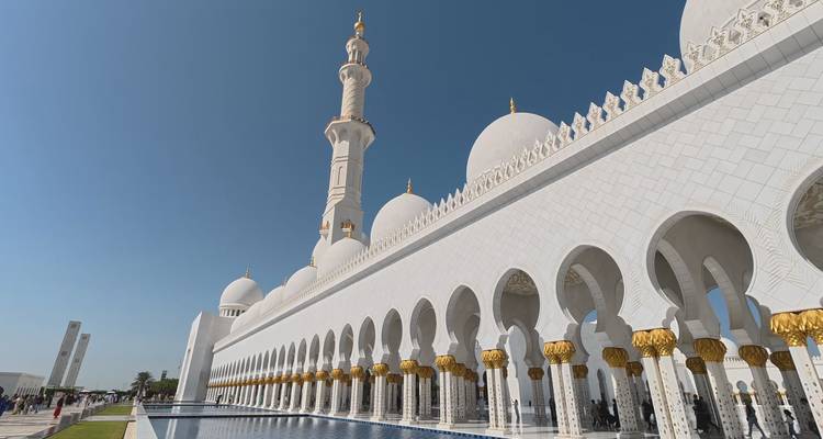 Side perspective of Sheikh Zayed Grand Mosque with reflective pools and gilded columns.