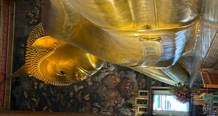 Golden Reclining Buddha inside richly decorated temple hall.