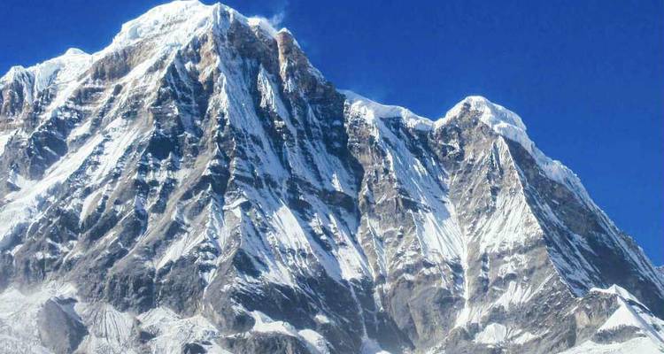 Los picos nevados del Annapurna brillan intensamente contra un cielo himalayo azul profundo.