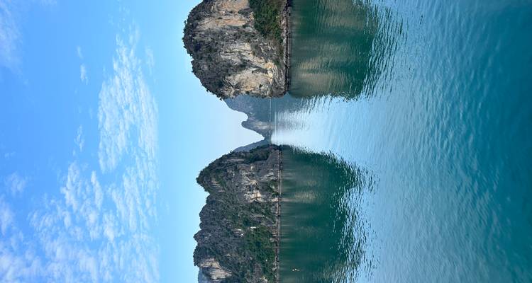 Icónicas islas kársticas reflejadas en las tranquilas aguas azules de la Bahía de Ha Long bajo un cielo brillante.