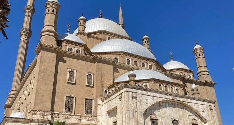 La mezquita de arenisca de Mohamed Alí con minaretes elevados y cúpulas blancas bajo un cielo azul claro de El Cairo.