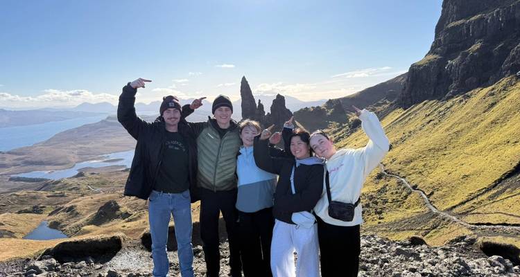 Cinq amis célèbrent au spectaculaire point de vue du Vieil Homme de Storr surplombant la mer et les falaises.