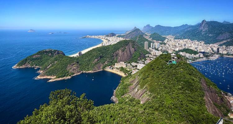 Vista aérea impresionante de la costa de Río de Janeiro, el Pan de Azúcar y el paisaje urbano contra un cielo azul brillante y el mar.