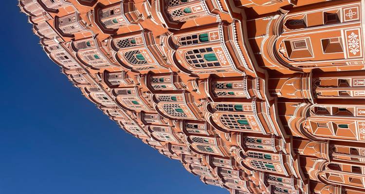 Angle ascendant de la façade ornée en grès rose du Hawa Mahal contre un ciel bleu vif à Jaipur