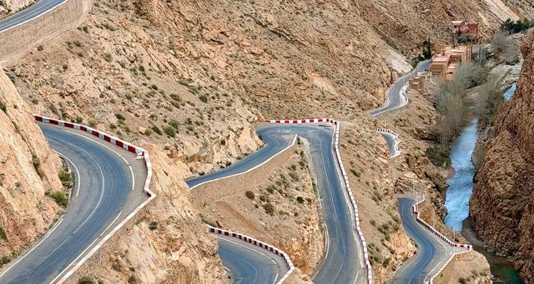 Carretera serpenteante dramática de montaña que serpentea a través de un desfiladero con un río en su base en Marruecos