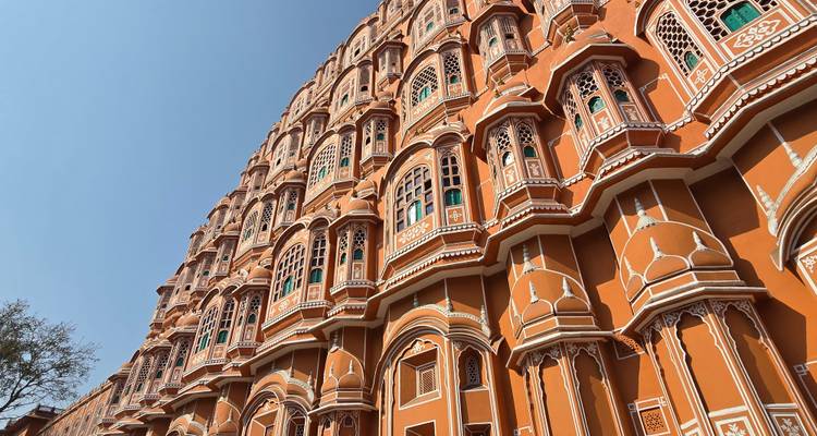 Ángulo ascendente de la ornamentada fachada de terracota del Hawa Mahal de Jaipur contra el cielo azul