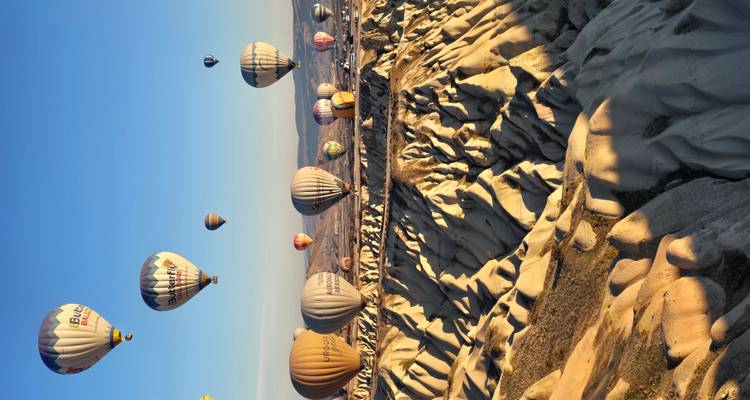 Docenas de coloridos globos aerostáticos flotan sobre los valles de roca esculpida de Capadocia al amanecer.