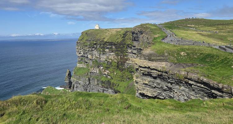 Dramatischer Blick auf die Cliffs of Moher mit O'Brien's Tower auf einer grasbewachsenen Landzunge mit Blick auf den Atlantischen Ozean.