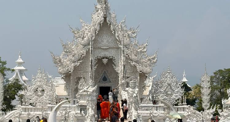 Le Wat Rong Khun (Temple Blanc) brille sous le soleil tandis que les visiteurs traversent son pont orné.