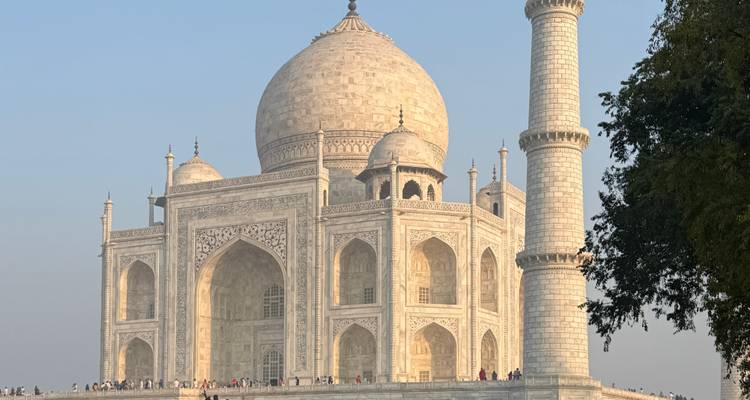Le Taj Mahal brillant dans une lumière douce avec des foules marchant le long de la plateforme.