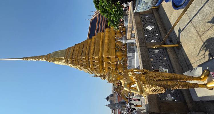 Chedi doré scintillant et statue de gardien au complexe du Grand Palais de Bangkok grouillant de visiteurs