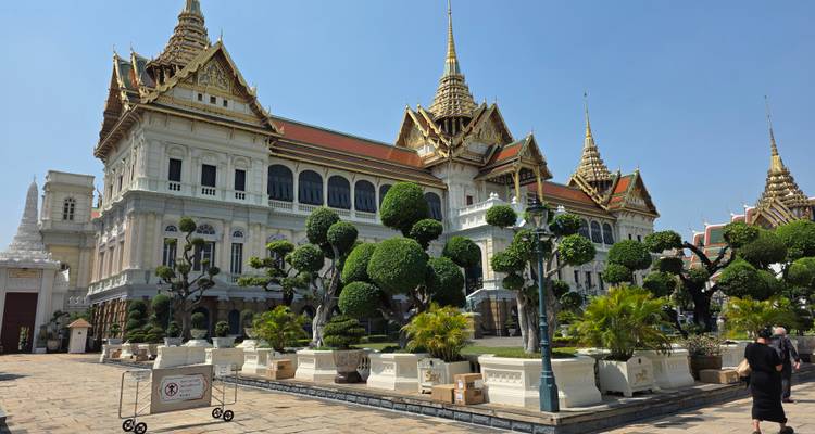 Élégant bâtiment de Grand Palais avec des arbres topiaires soignés et des flèches dorées contre un ciel bleu clair