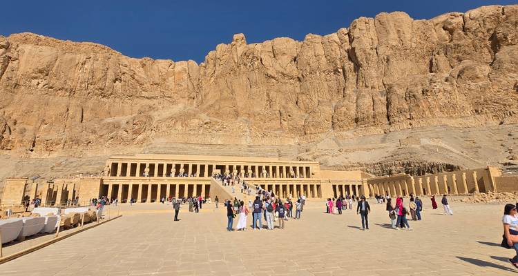 Terrasvormige Tempel van Hatshepsut tegen torenhoge zandstenen kliffen met toeristen die over het plein wandelen