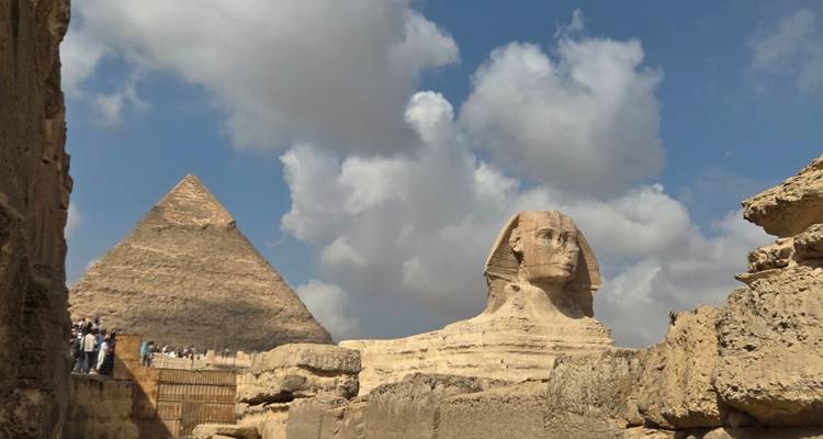 Vooraanzicht van de Sfinx met een piramide op de achtergrond en dramatische wolken in de lucht