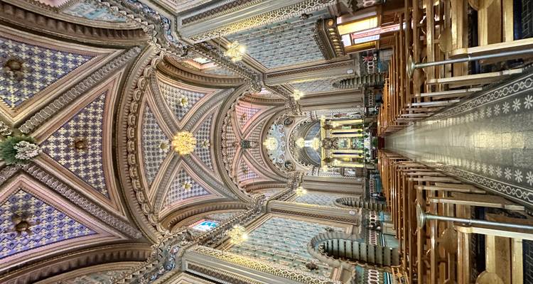 Grand intérieur d'église orné de carrelages avec de hauts plafonds voûtés, des lustres et des bancs en bois menant vers l'autel