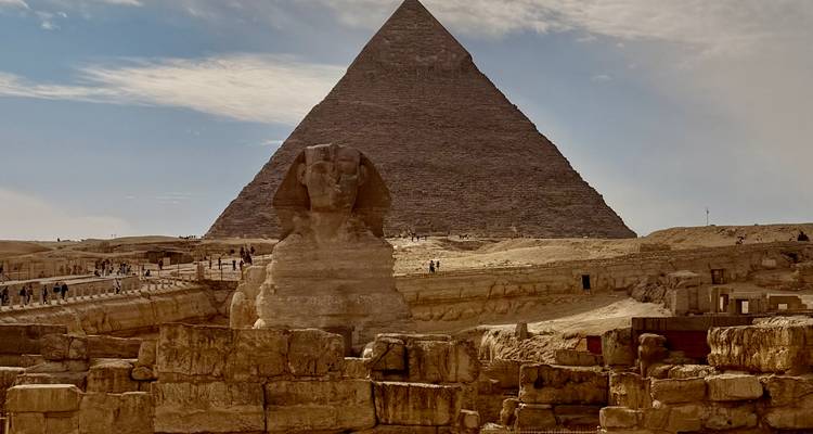 La Gran Pirámide de Giza se alza detrás de la Esfinge bajo cielos parcialmente nublados.