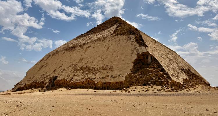 La distintiva Pirámide Acodada se alza desde las arenas del desierto bajo un cielo brillante.