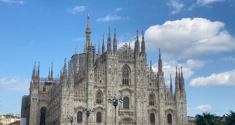 Vista frontal detallada de la ornamentada catedral gótica de Milán bajo un cielo brillante