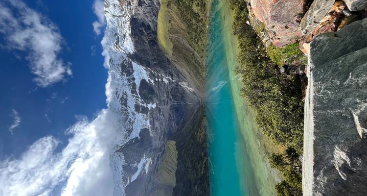 Brillante lago Humantay de color turquesa reflejando picos nevados bajo un cielo dramático.