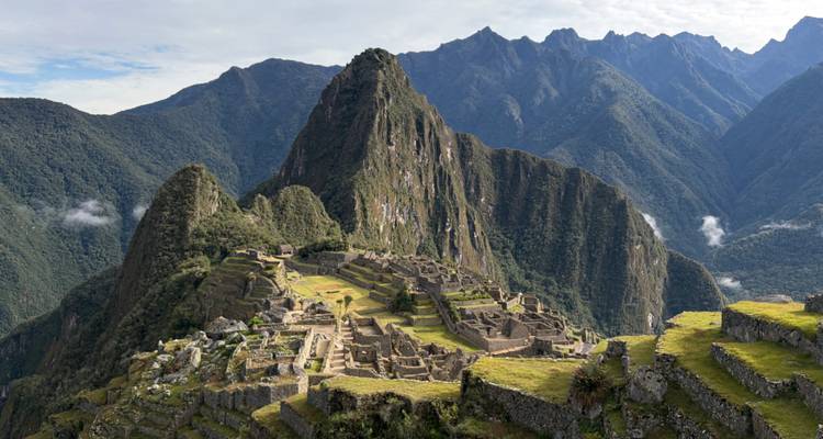 Panoramablick auf die vollständige Zitadelle von Machu Picchu mit dramatischen grünen Gipfeln im Hintergrund.
