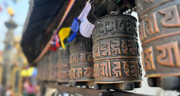 Primer plano de ruedas de oración tibetanas de bronce con escritura decorativa en un sitio budista.