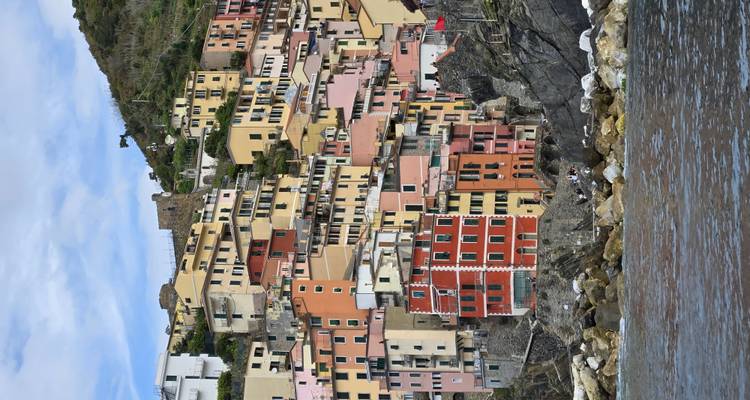 Casas coloridas del acantilado de Riomaggiore elevándose sobre la costa rocosa