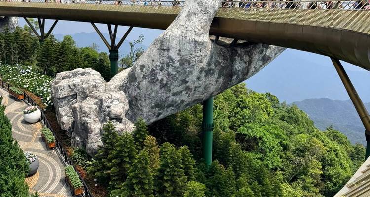 Golden Bridge held by giant stone hand above lush forested hills