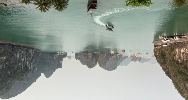 Panoramic view over emerald waters dotted with karst islets and cruising boats