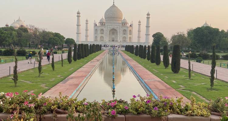 Vue frontale emblématique du Taj Mahal se reflétant dans son long canal d'eau à la lumière du coucher de soleil.