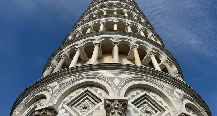 Vista dramática de gusano de la Torre Inclinada de Pisa contra un cielo azul profundo.