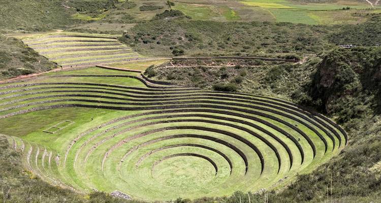Terrassenförmige konzentrische landwirtschaftliche Kreise der archäologischen Stätte Moray, umgeben von grünen Feldern.