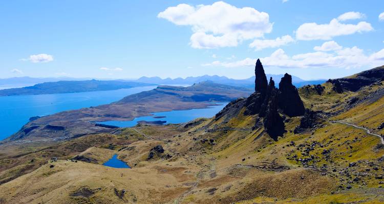 Dramatische Felsspitzen des Old Man of Storr mit Blick auf blaue Meeresarme und entfernte Inseln.