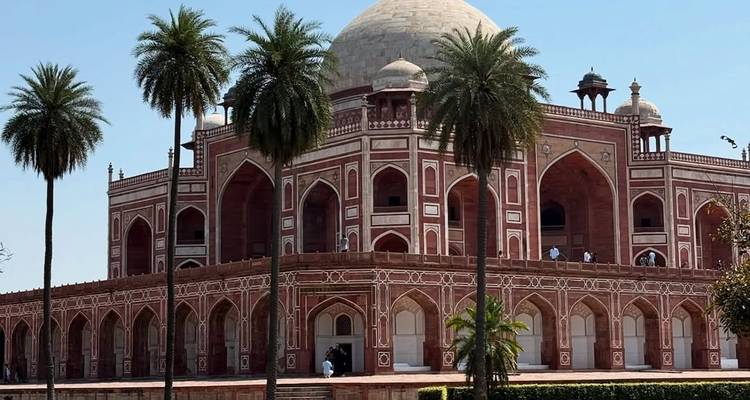 Le tombeau de Humayun à Delhi encadré par des palmiers sous un ciel bleu éclatant.