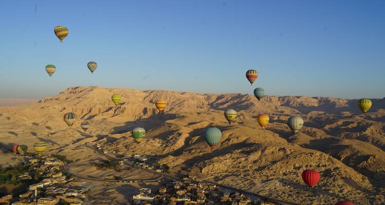 Des dizaines de montgolfières colorées flottant au-dessus des montagnes désertiques accidentées de Louxor au lever du soleil.