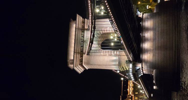 Dramatic night shot of Budapest’s Chain Bridge lit by strings of lights reflecting on the Danube.