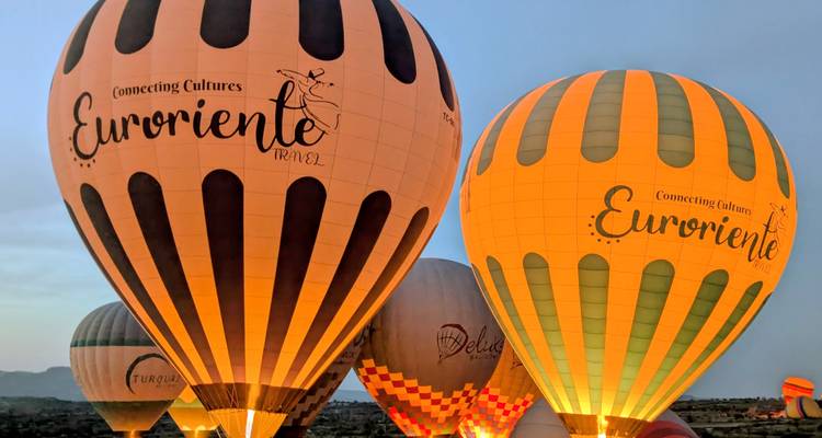 Des montgolfières illuminées se préparent au décollage en Cappadoce dans la lumière de l'aube naissante.