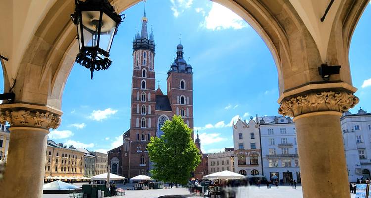 La Basilique Sainte-Marie encadrée par une arche sur la place principale de Cracovie sous un ciel bleu.