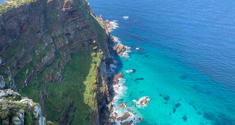 Dramatic cliff dropping to bright turquoise waters at Cape Point on a sunny day