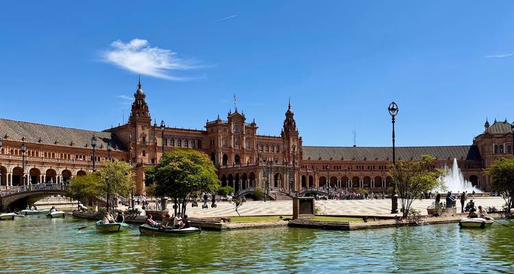 Plaza de España à Séville avec des barques à rames sur le canal et des tours ornées sous un ciel bleu