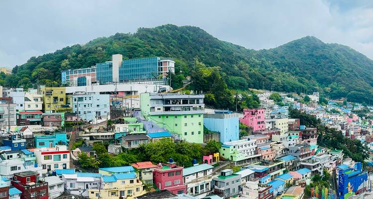 Coloridas casas en la ladera de la aldea cultural de Gamcheon respaldadas por montañas verdes bajo un cielo brumoso
