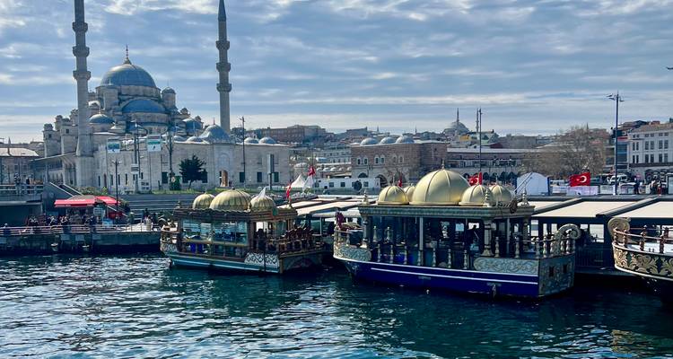 Les restaurants flottants aux dômes dorés amarrés devant la Nouvelle Mosquée d'Istanbul le long d'un quai animé.