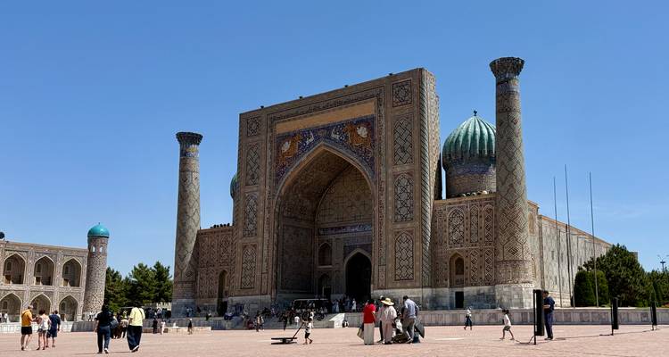 Grand Registan square in Samarkand with stunning mosaic-covered madrasa under a clear sky.