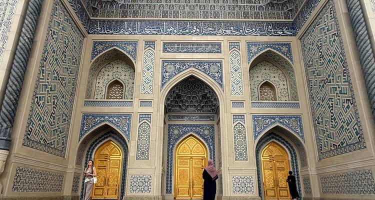 Intricately tiled entrance of a mosque in Tashkent featuring golden doors and blue geometric patterns.