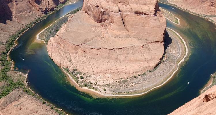 Vue aérienne du virage en fer à cheval spectaculaire d'une rivière bleu profond s'incurvant autour d'une mesa de grès.
