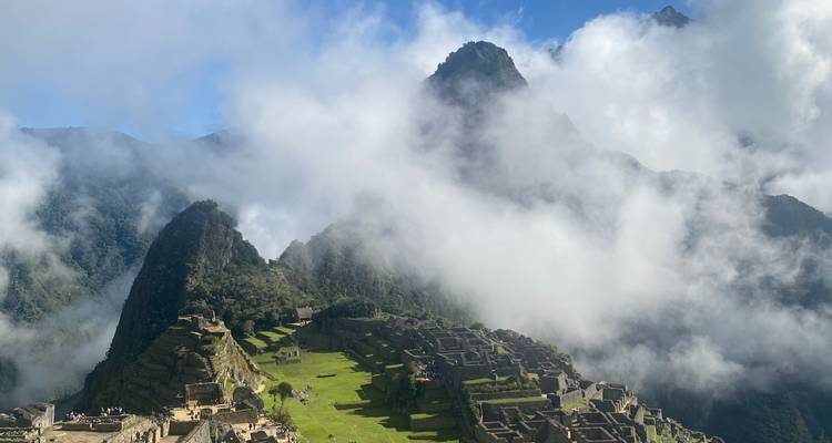 Vue panoramique emblématique des ruines du Machu Picchu entourées de pics verdoyants luxuriants et de nuages qui s'étirent.