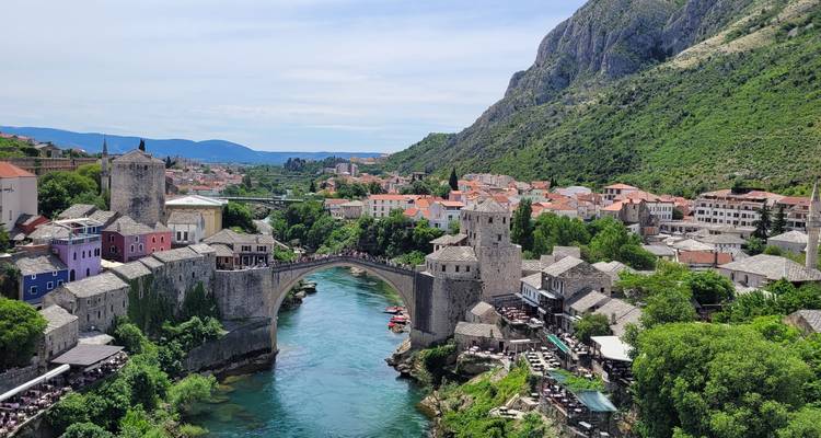 Vista clásica de postal del Puente Viejo de Mostar arqueándose sobre el río Neretva de color esmeralda rodeado de tejados naranjas
