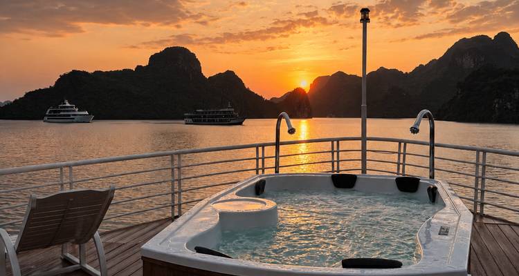 Bain à remous sur le pont d'une croisière face aux îles calcaires spectaculaires alors que le soleil se couche sur la baie d'Halong.
